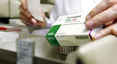 Nahaufnahme einer Hand, die eine Packung Amoxypen-Tabletten aus einer Apotheke entnimmt.